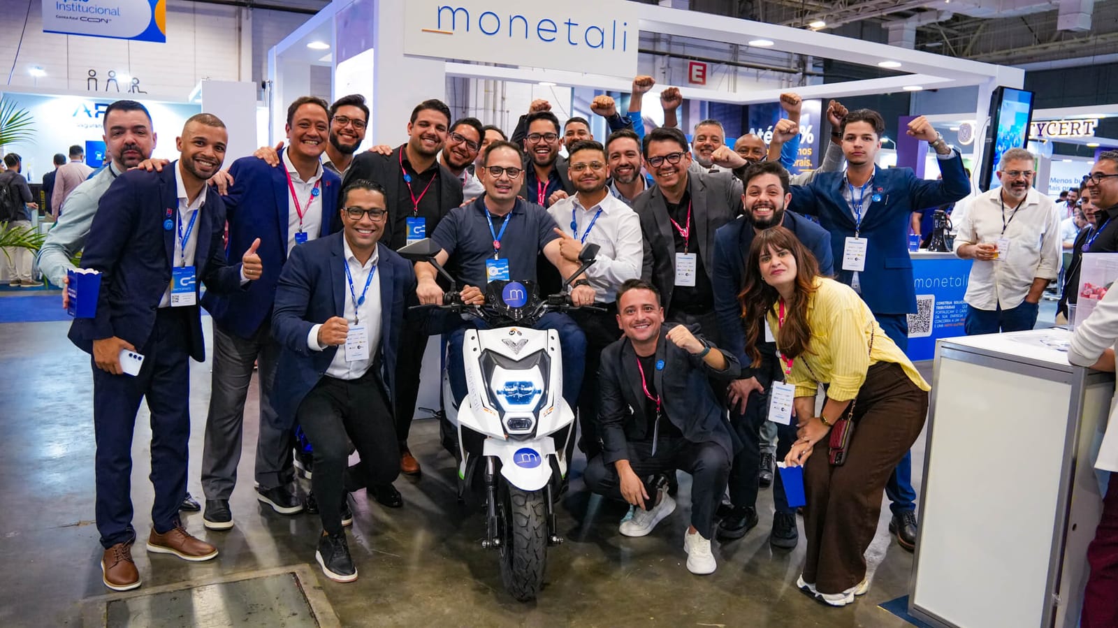 Equipe Monetali reunida no estande ao lado da moto elétrica sorteada entre os visitantes